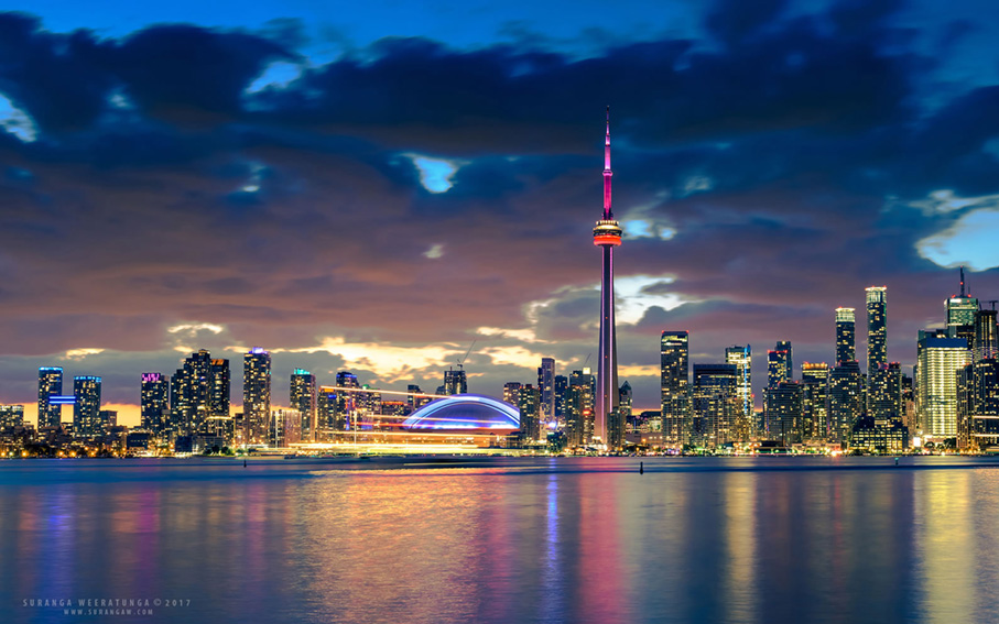 A Canadian city skyline lit up at dusk across the water